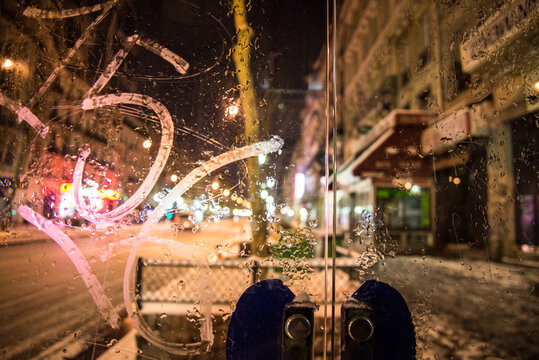 Snowy and frozen reflections of Paris at nigh seen through a phone cabine