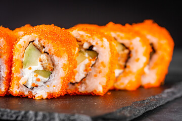 appetizing sushi roll california with eel cheese cucumber avocado and caviar masago on a black stone plate