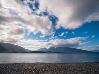 Lake Te Anau Panoramic view at golden hour on the rocky shore at Te Anau with the mountain range in the background in Fiordland National Park, New Zealand, South Island.