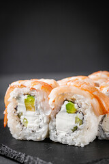 appetizing sushi roll philadelphia with avocado cheese cucumber and shrimp on a black stone plate