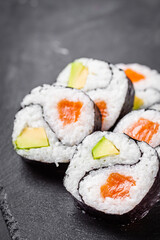 appetizing sushi roll futomaki yin yang with salmon and avocado on a black stone plate