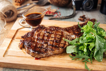 Closeup on grilled beef meat steak with pepper sauce on the wooden board
