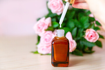 Pipette with a drop of cosmetic serum over glass bottles 