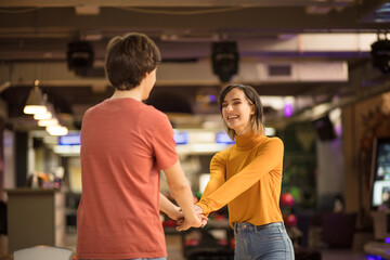 Young couple having fun in bowling alley.  Holding hands. Focus is on girl.