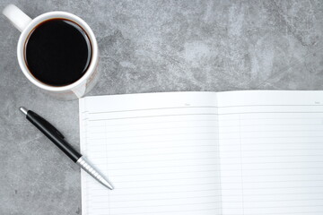 coffee, blank notebook and a pen on cement concrete surface floor.