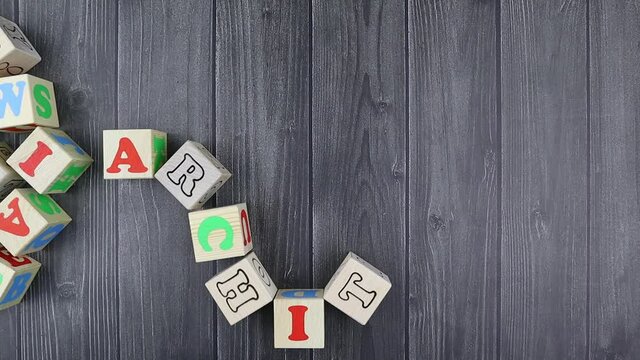 Colourful wooden toy alphabet blocks spelling word - Architecture over a dark grey plank background with copyspace. Stop motion, top view