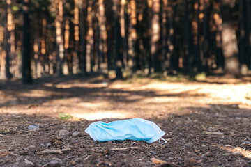 Surgical mask lying on the ground in the middle of a path in the forest