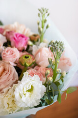 Beautiful wedding bouquet on bright background. Bouquet consists of pink roses, ranunculus, eucalyptus