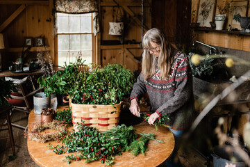 florist making holiday wreath with evergreen and holly