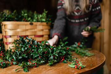florist making holiday wreath with holly