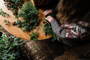 florist making holiday wreath with holly
