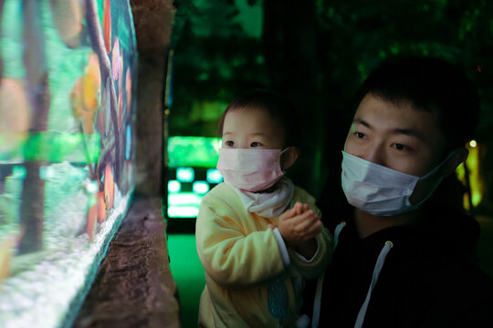 Father and daughter wearing masks visiting the aquarium