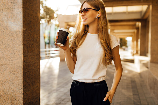 young woman in sunglasses walking in city with cell phone