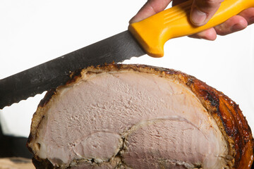  Mano con un coltello giallo taglia una fetta di roast-beef poggiato su un tavolo