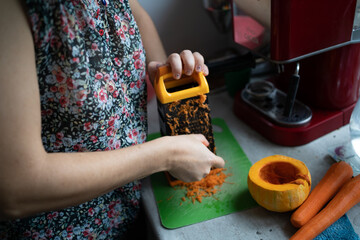 Woman rubs carrots for further cooking