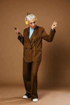 Elegant aged woman listening to music and snapping fingers