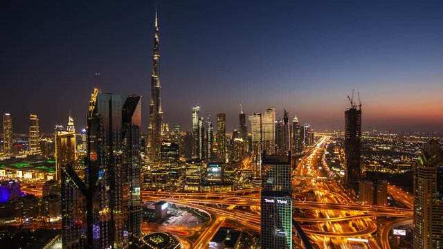 Day to night timelapse of Dubai city center with modern tall skyscrapers and busy street traffic on a highway. Time lapse of Dubai with bright city lights at night