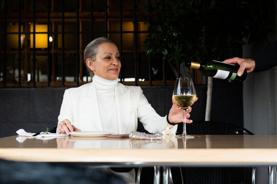 Woman waiting for the waiter to serve wine