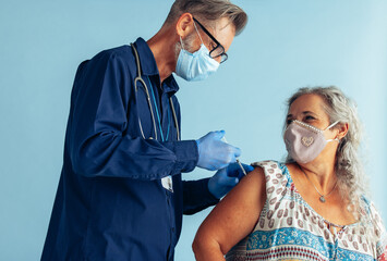 Doctor giving covid vaccine to senior woman