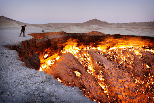 A traveller peers into the flaming Darvaza gas crater in the desert of Turkmenistan.