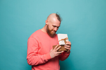 Bearded european man in casual peach isolated on turquoise background excited opening gift box