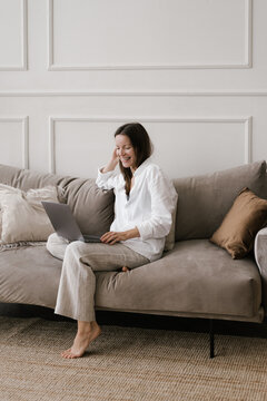 Happy Woman Using Laptop On Sofa