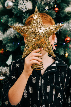 Holding christmas tree star decoration over face
