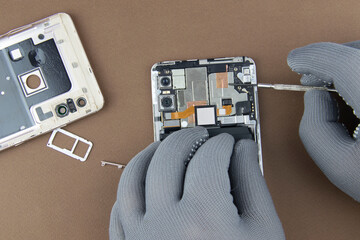 men's hands in special gloves repair a smartphone. the concept of computer hardware, mobile phone,...