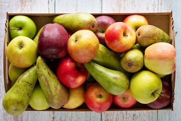 Ripe apples and pears close-up in a wooden box. Top view.