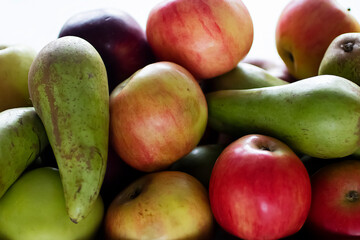 Ripe apples and pears close-up in a wooden box.