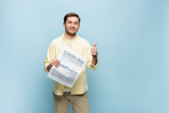 Smiling Man In Shirt Holding Newspaper And Showing Thumb Up Isolated On Blue