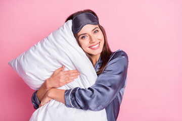 Photo portrait of adorable girl hugging pillow isolated on pastel pink colored background