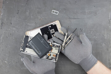 men's hands in special gloves repair a smartphone. the concept of computer hardware, mobile phone,...