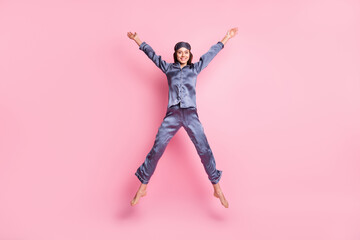 Fototapeta na wymiar Full length body size photo of girl wearing blue nightwear jumping playful like star smiling isolated on pastel pink color background