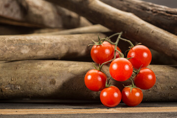 grappolo di pomodori davanti a dei tronchi di legno 
