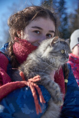 Focus on the girl's face.A fluffy gray cat with huge eyes in the girl's arms.