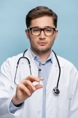 Fototapeta premium blurred doctor in glasses and white coat holding syringe with vaccine isolated on blue