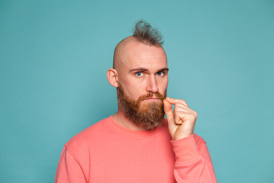 Bearded european man in casual peach isolated on turquoise background mouth and lips shut as zip with fingers