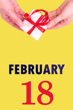 February 18th. Festive Vertical Calendar With Hands Holding White Gift Box With Red Ribbon And Calendar Date 18 February On Illuminating Yellow Background. Winter month, day of the year concept.
