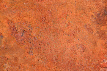 The texture of an old metal surface coated with a layered orange rust.