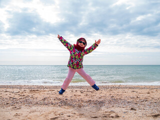 Little girl jumping on empty sand beach and flying in the air. Lifestyle photo real people. Scenic marine landscape Vivid blue sea water sky.Happy active family having fun on vacation travel wallpaper