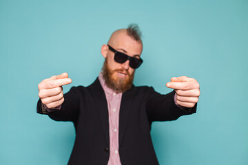 Naklejka premium Bearded european businessman in dark suit isolated on turquoise background shows money gesture, asking for help