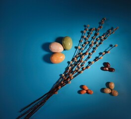 Top-Down Easter Decoration Isolated on Blue Background. Colorful Eastern Eggs and Twig of Pussy Willow.