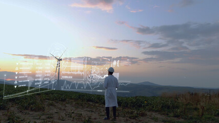 Adult man in white uniform working on wind farm on sunset using futuristic technology with 3d model construction of windmill buildings. Agronomy business. Tech innovation. Hi-tech concept.Human future