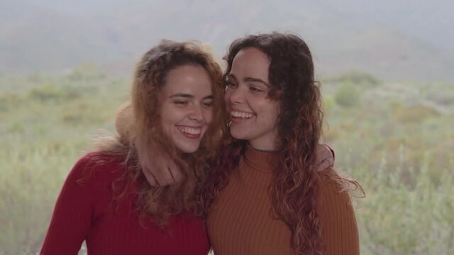 Hermanas gemelas se dan abrazos mostrando amistad, felicidad y complicidad en un d&iacute;a nublado