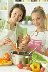  girl with her mother cooking together at kitchen