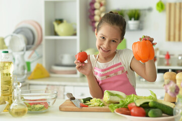 Obraz na płótnie Canvas Cute girl preparing delicious fresh salad in kitchen