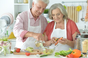 Senior couple making salad together at kitchen