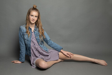 very young charming barefooted woman teenager girl sitting in studio on gray background, long legs....