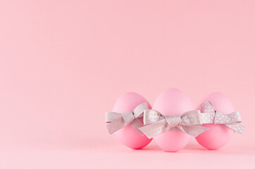 Cute and naivety easter background with pink eggs group with grey bows on pastel pink backdrop.